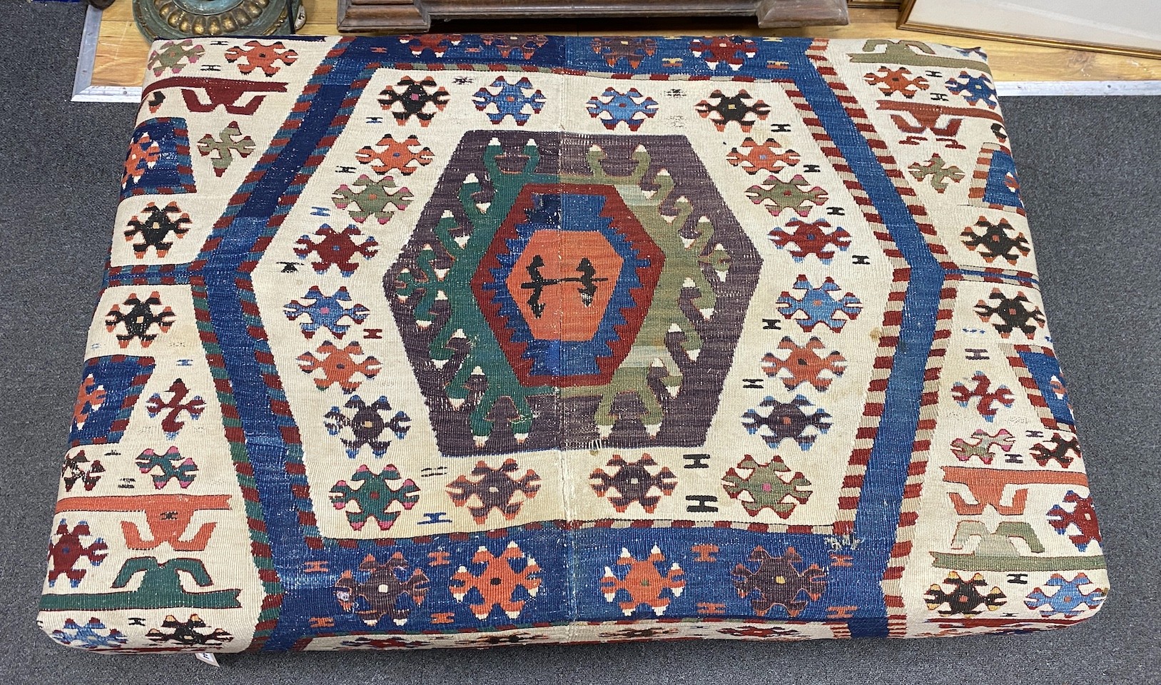 A large rectangular coffee table / footstool with antique kelim upholstery on stained turned beech feet, width 107cms, depth 72cms, height 37cms.